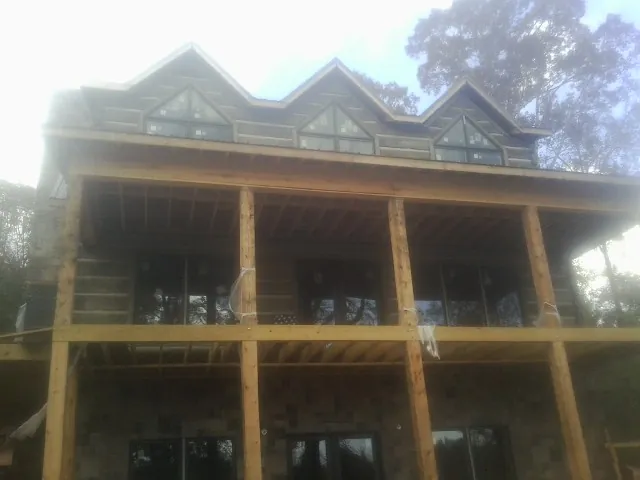 Dormers and porch framing on a large log home under construction — Roof Coating work by our crew in Silverton