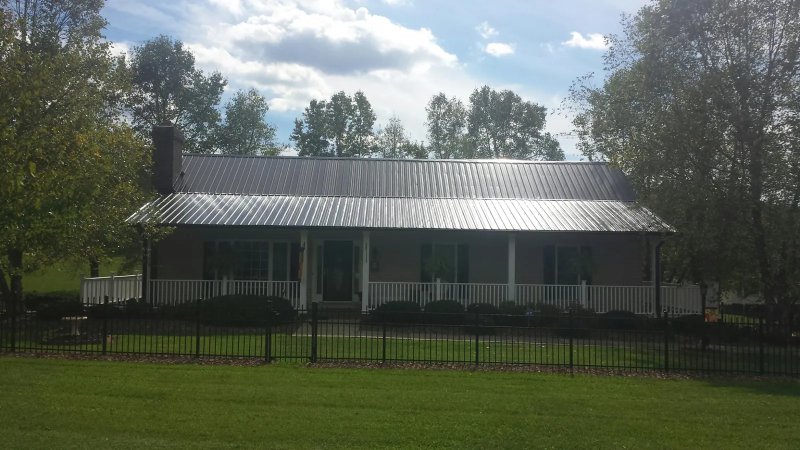 Gray metal roof on a brick ranch with a full width front porch — Gutter Guard Installation work by our crew in Silverton