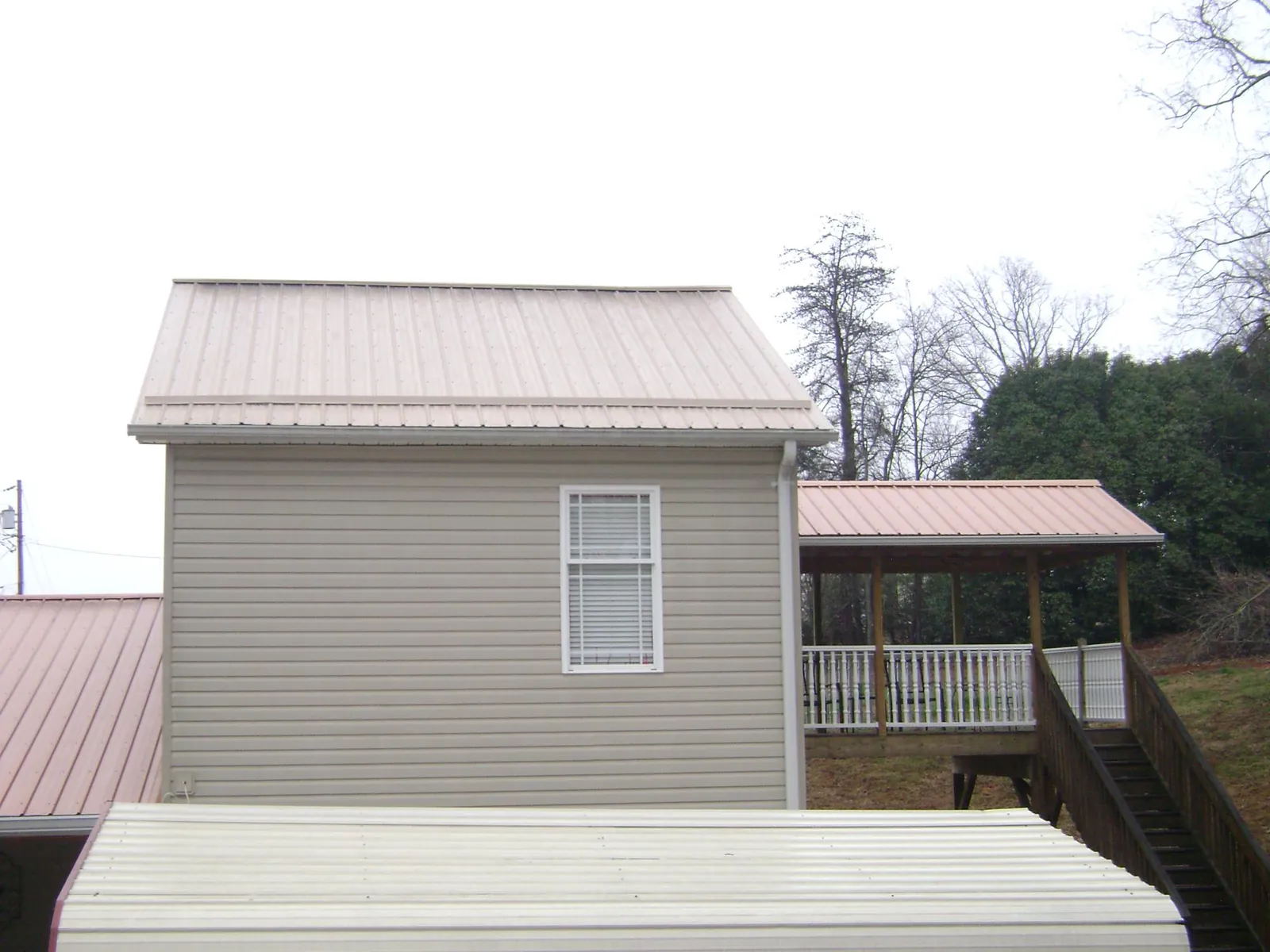 Tan metal roofs on a two story addition and attached porch, from a Roof Replacement job in Silverton
