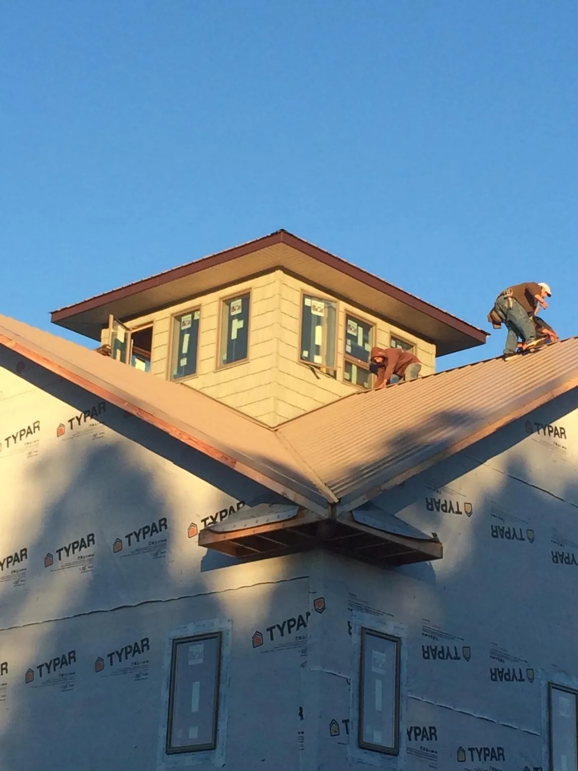 Roofers working around a rooftop cupola on a new metal roof at sunset — Roof Waterproofing in Silverton by Roofing Brothers